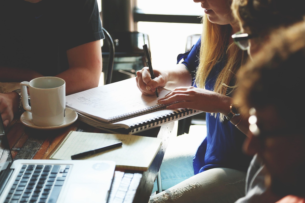 Hands, notebook, and laptop on a wooden table during a household money review